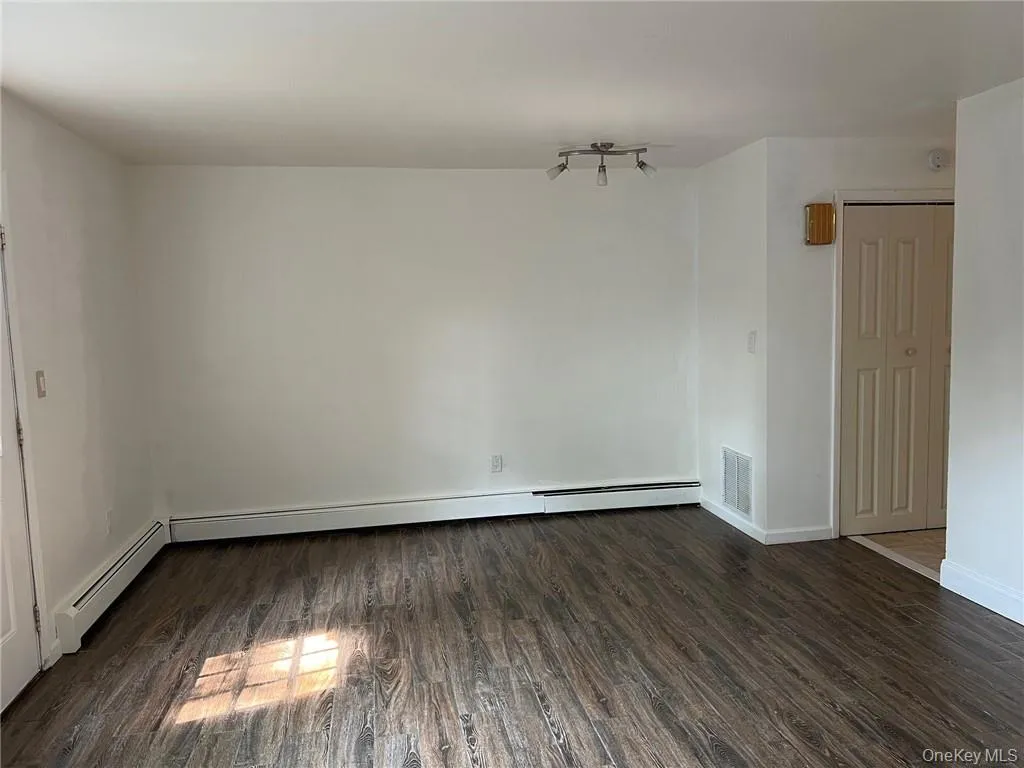 Another angle of liivng room featuring dark wood-type flooring and baseboard heating. Another angle of liivng room featuring dark wood-type flooring and baseboard heating.