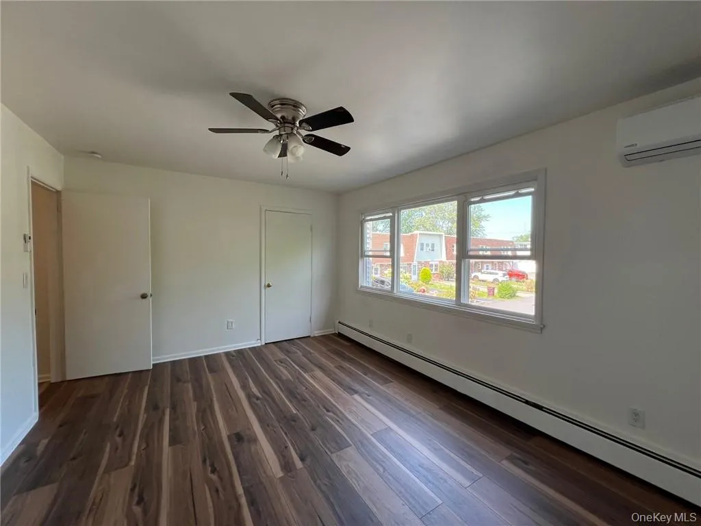 Bedroom #1 bedroom featuring a wall mounted AC, dark hardwood / wood-style flooring, a baseboard heating unit, and ceiling fan Bedroom #1 bedroom featuring a wall mounted AC, dark hardwood / wood-style flooring, a baseboard heating unit, and ceiling fan