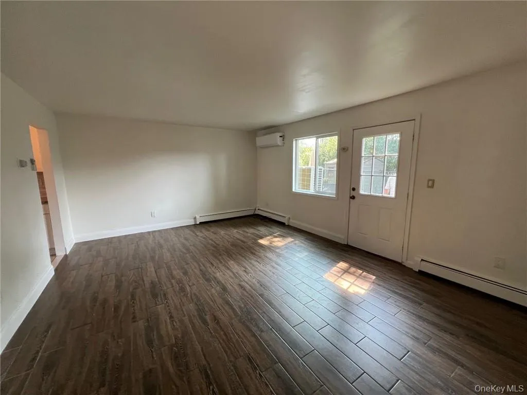 Dining room/living room combination with a wall mounted AC, baseboard heating, and dark hardwood / wood-style flooring Dining room/living room combination with a wall mounted AC, baseboard heating, and dark hardwood / wood-style flooring