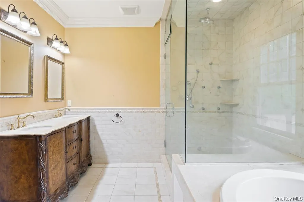 Bathroom with light tile patterned floors, tile walls, a garden tub, a shower stall, and double vanity Bathroom with light tile patterned floors, tile walls, a garden tub, a shower stall, and double vanity