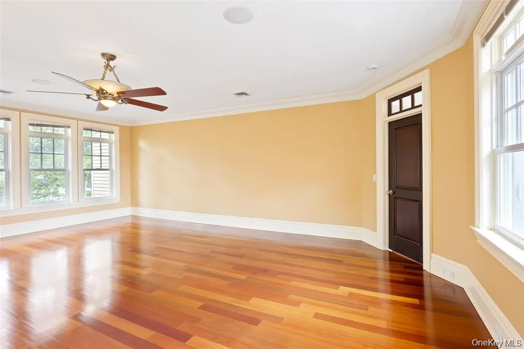 Empty room featuring ornamental molding, light wood-style floors, and a ceiling fan Empty room featuring ornamental molding, light wood-style floors, and a ceiling fan