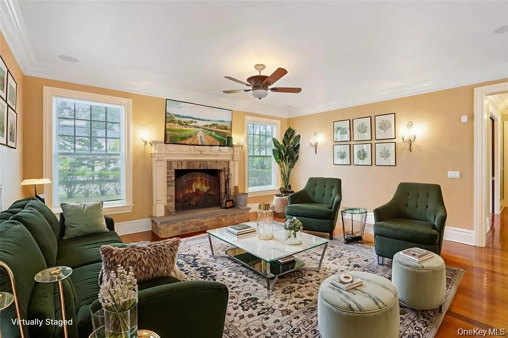 Living area with wood finished floors, crown molding, a ceiling fan, and a fireplace Living area with wood finished floors, crown molding, a ceiling fan, and a fireplace