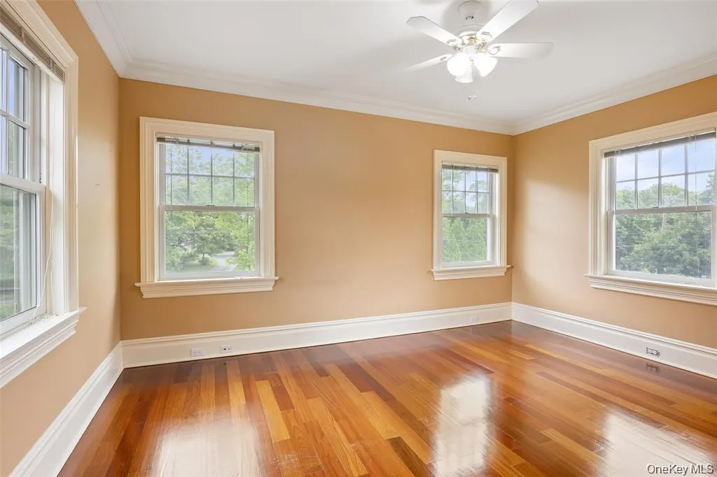 Unfurnished room with crown molding, wood finished floors, and ceiling fan Unfurnished room with crown molding, wood finished floors, and ceiling fan