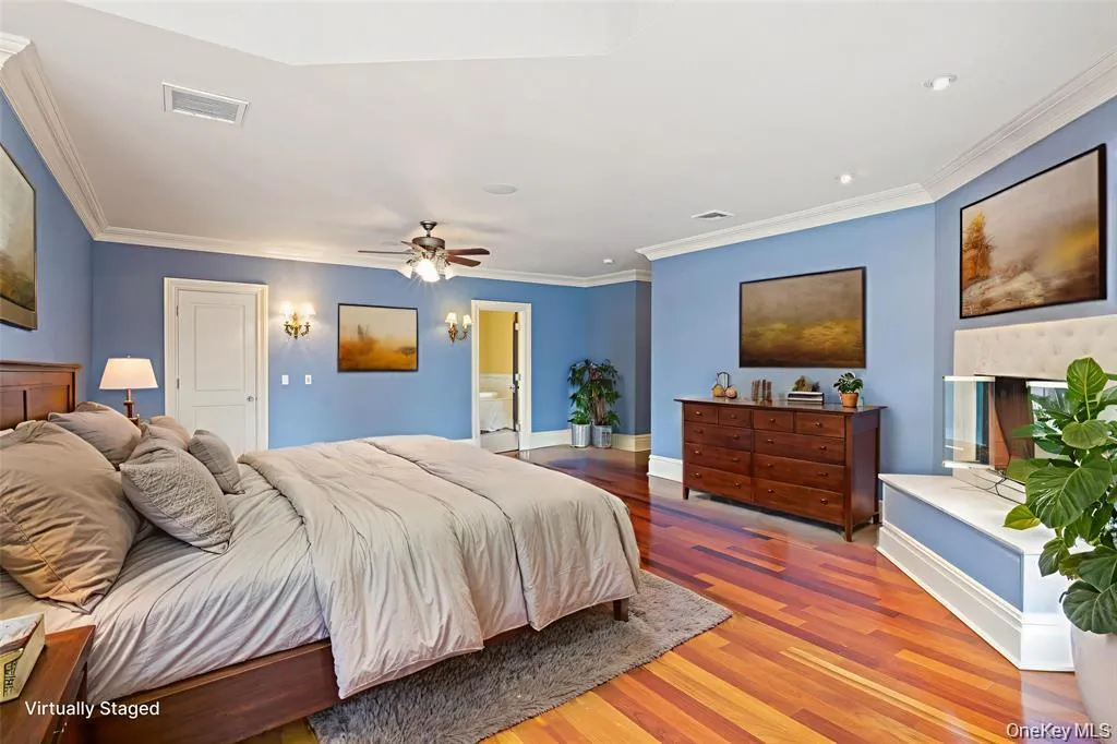 Bedroom with wood finished floors, crown molding, a fireplace, and a ceiling fan Bedroom with wood finished floors, crown molding, a fireplace, and a ceiling fan
