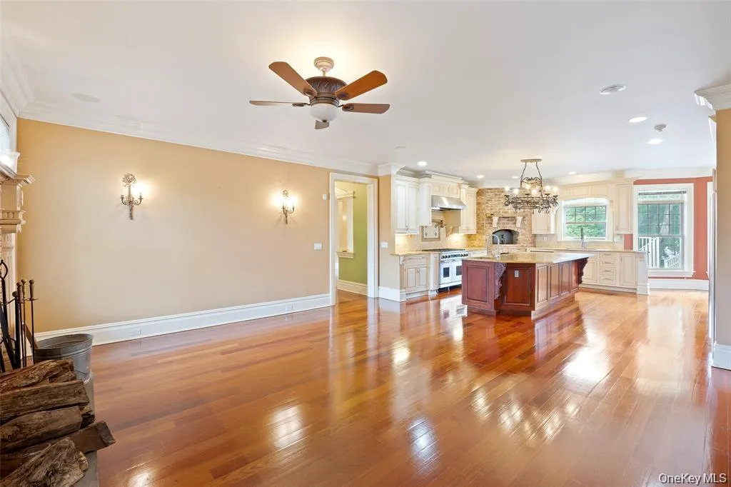 Living area with a brick fireplace, light wood-type flooring, ornamental molding, a ceiling fan, and recessed lighting Living area with a brick fireplace, light wood-type flooring, ornamental molding, a ceiling fan, and recessed lighting