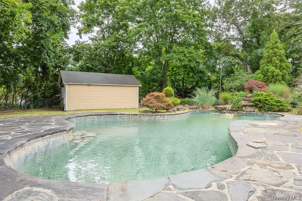 Outdoor pool with view of scattered trees, an outbuilding, and a patio area Outdoor pool with view of scattered trees, an outbuilding, and a patio area
