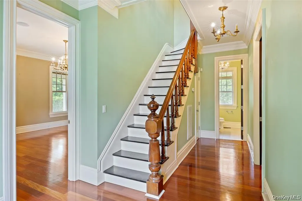 Staircase with a chandelier, crown molding, and hardwood / wood-style flooring Staircase with a chandelier, crown molding, and hardwood / wood-style flooring