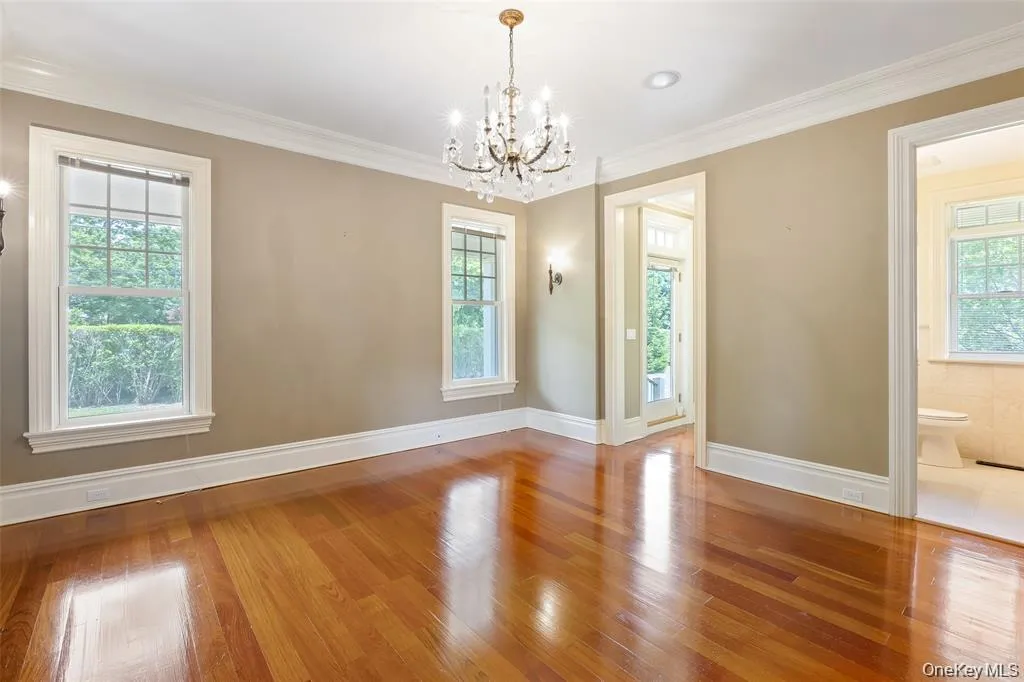 Unfurnished dining area featuring wood-type flooring, crown molding, and a chandelier Unfurnished dining area featuring wood-type flooring, crown molding, and a chandelier