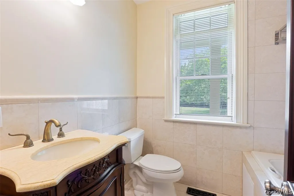 Bathroom with vanity, a garden tub, tile walls, wainscoting, and tile patterned floors Bathroom with vanity, a garden tub, tile walls, wainscoting, and tile patterned floors