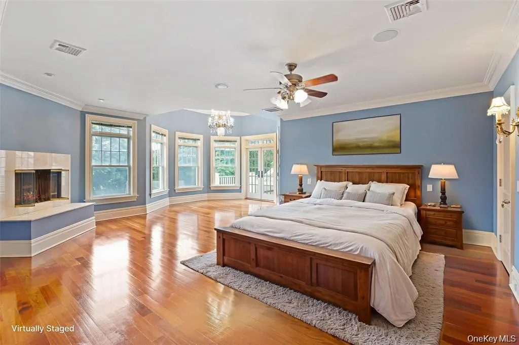 Bedroom featuring ornamental molding, a multi sided fireplace, light wood-style floors, a chandelier, and ceiling fan Bedroom featuring ornamental molding, a multi sided fireplace, light wood-style floors, a chandelier, and ceiling fan
