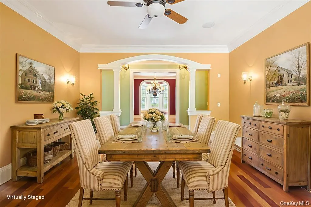 Dining area with ornamental molding, wood finished floors, a chandelier, ornate columns, and arched walkways Dining area with ornamental molding, wood finished floors, a chandelier, ornate columns, and arched walkways