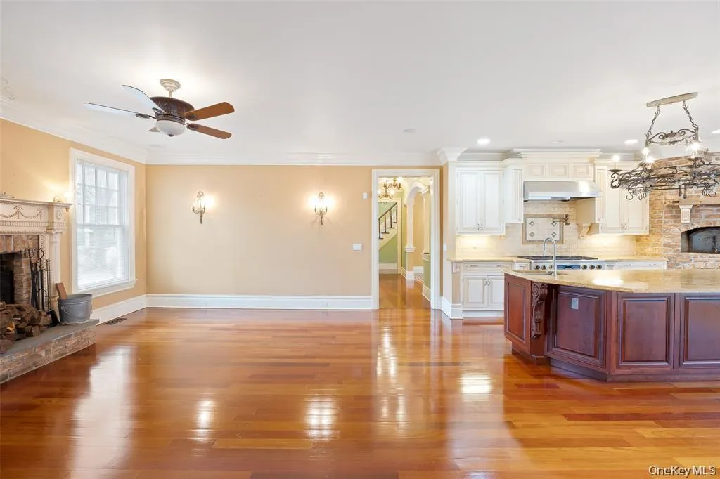 Kitchen with a fireplace with raised hearth, open floor plan, backsplash, light wood finished floors, and ornamental molding Kitchen with a fireplace with raised hearth, open floor plan, backsplash, light wood finished floors, and ornamental molding