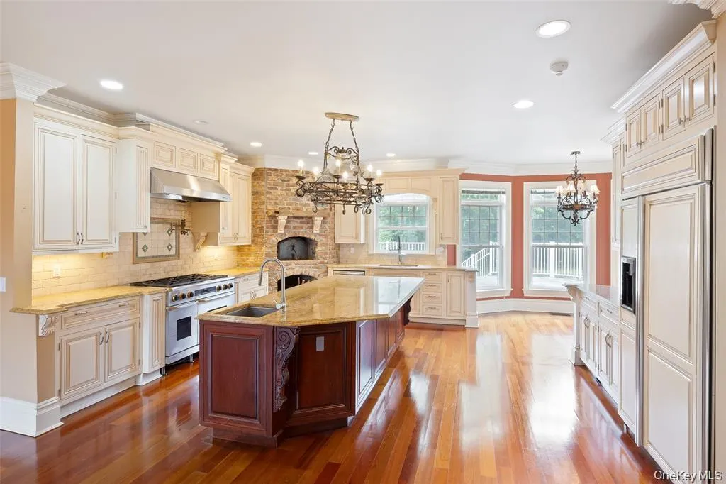 Kitchen with decorative light fixtures, backsplash, light stone counters, high quality appliances, and dark wood finished floors Kitchen with decorative light fixtures, backsplash, light stone counters, high quality appliances, and dark wood finished floors