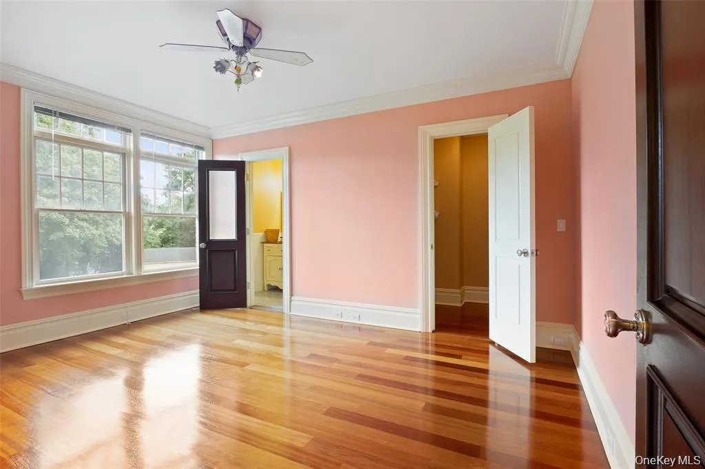 Unfurnished bedroom featuring crown molding, light wood-style floors, a ceiling fan, and connected bathroom Unfurnished bedroom featuring crown molding, light wood-style floors, a ceiling fan, and connected bathroom