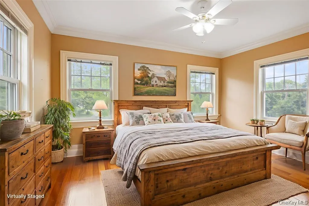 Bedroom with crown molding, wood finished floors, and a ceiling fan Bedroom with crown molding, wood finished floors, and a ceiling fan