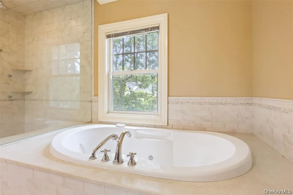 Full bath featuring a jetted tub and tiled shower Full bath featuring a jetted tub and tiled shower