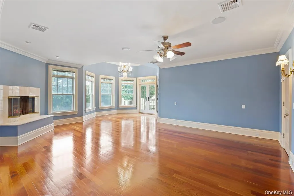 Unfurnished living room featuring ornamental molding, a high end fireplace, a chandelier, plenty of natural light, and wood finished floors Unfurnished living room featuring ornamental molding, a high end fireplace, a chandelier, plenty of natural light, and wood finished floors
