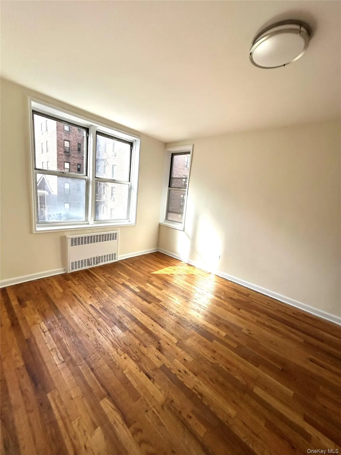 Empty room featuring radiator and hardwood / wood-style flooring Empty room featuring radiator and hardwood / wood-style flooring