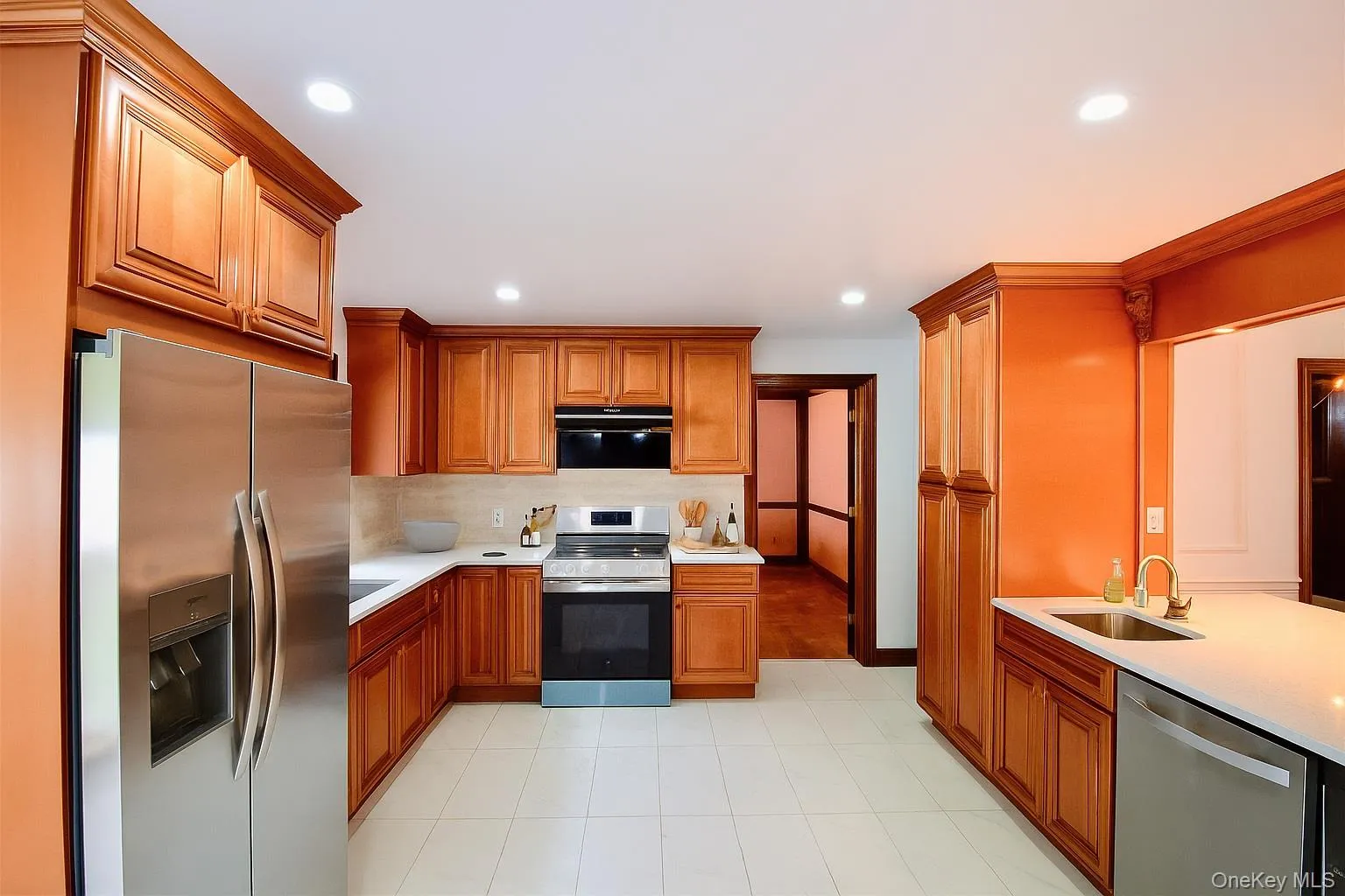 Kitchen featuring appliances with stainless steel finishes, brown cabinets, light stone countertops, recessed lighting, and tasteful backsplash Kitchen featuring appliances with stainless steel finishes, brown cabinets, light stone countertops, recessed lighting, and tasteful backsplash