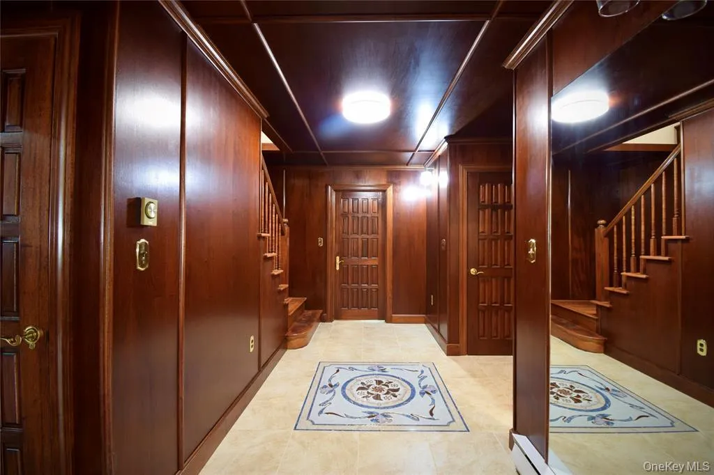 Corridor with stairs, wood walls, and light tile patterned floors Corridor with stairs, wood walls, and light tile patterned floors