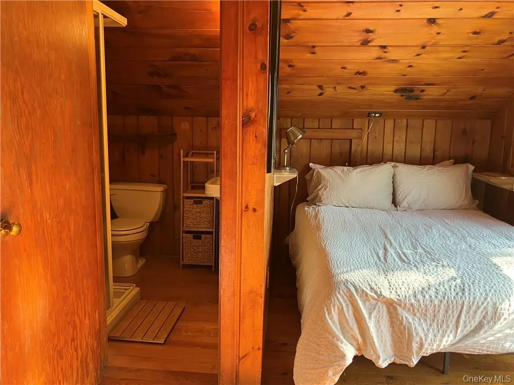Bedroom featuring hardwood / wood-style floors and wooden walls Bedroom featuring hardwood / wood-style floors and wooden walls