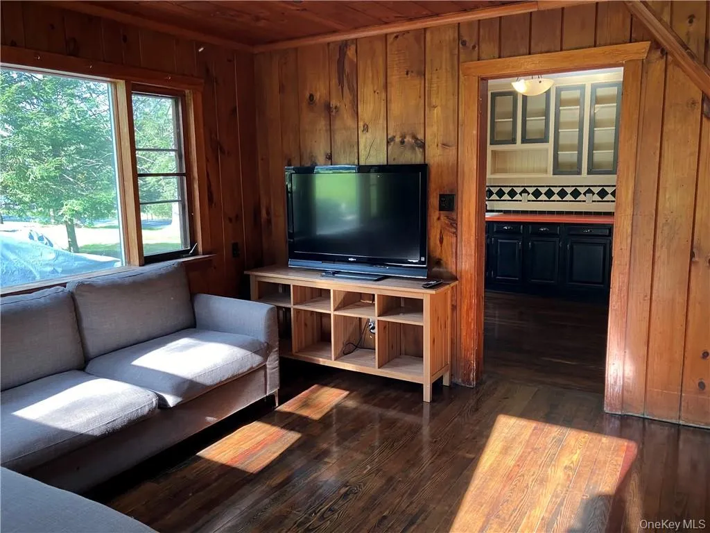 Living room with wooden ceiling, dark hardwood / wood-style flooring, and wood walls Living room with wooden ceiling, dark hardwood / wood-style flooring, and wood walls