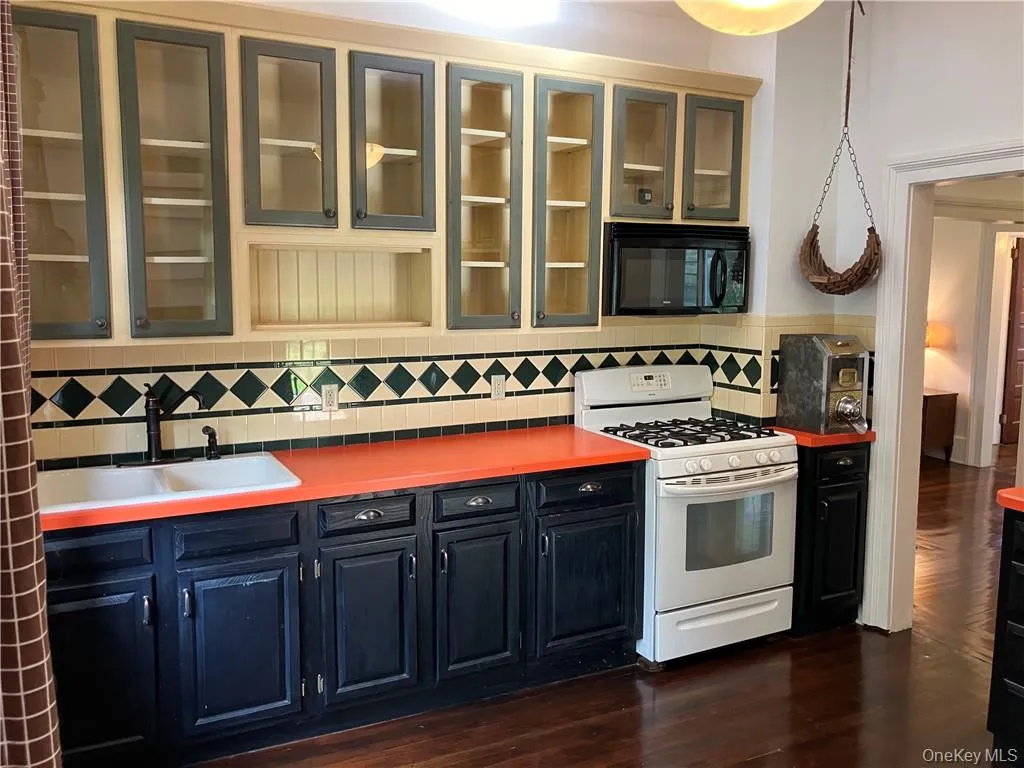 Kitchen featuring white gas range oven, sink, backsplash, and dark hardwood / wood-style flooring Kitchen featuring white gas range oven, sink, backsplash, and dark hardwood / wood-style flooring