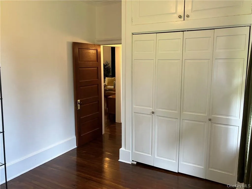Unfurnished bedroom with ornamental molding, dark wood-type flooring, and a closet Unfurnished bedroom with ornamental molding, dark wood-type flooring, and a closet