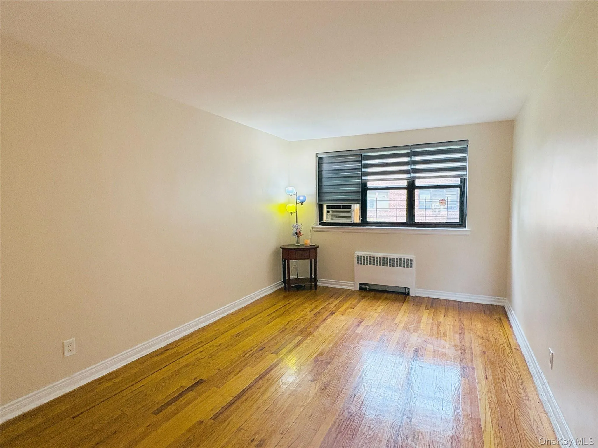 Bright room featuring wood-finish flooring, light-toned walls, and white baseboards Bright room featuring wood-finish flooring, light-toned walls, and white baseboards