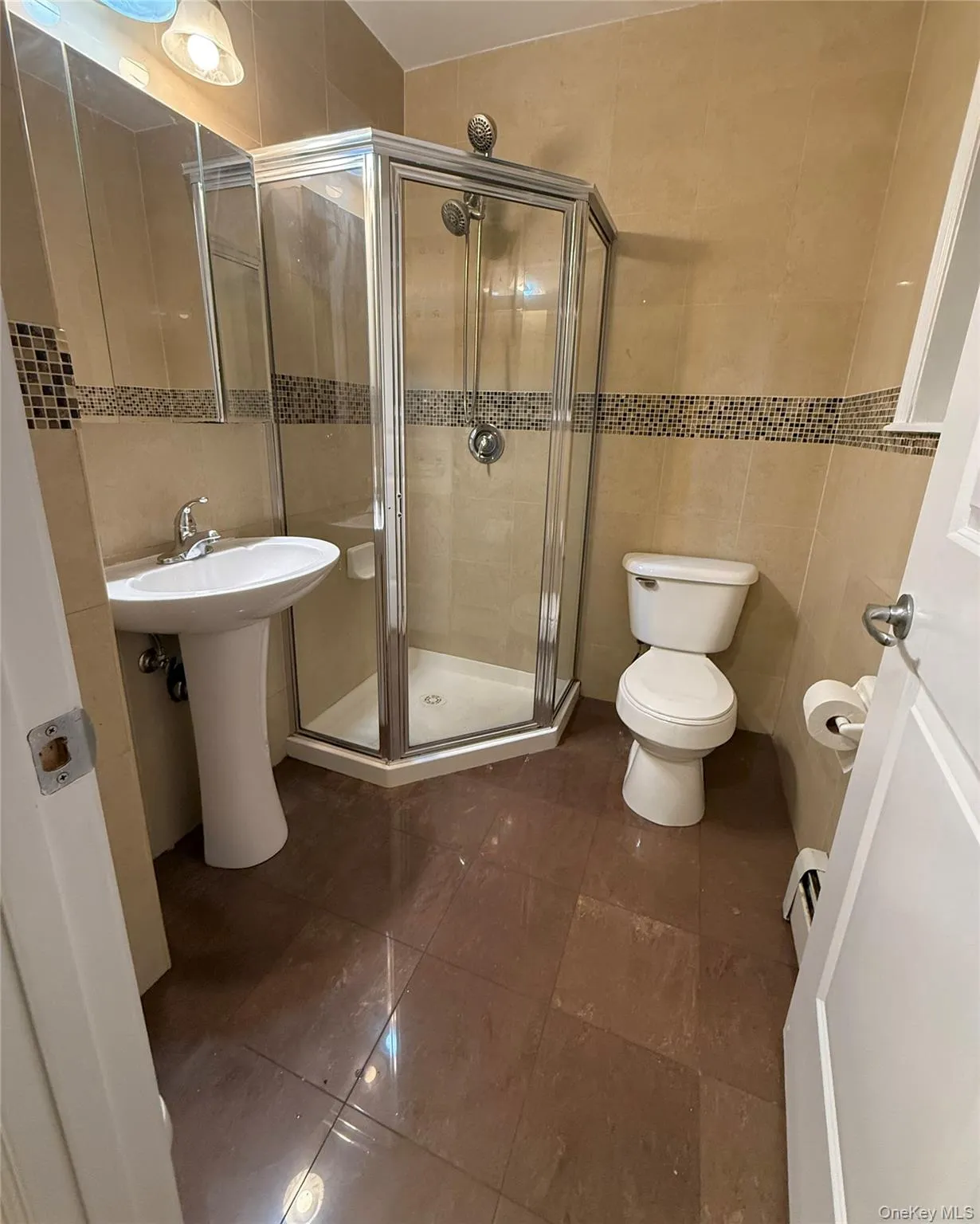 Full bath with tile walls, a shower stall, and dark tile patterned floors Full bath with tile walls, a shower stall, and dark tile patterned floors