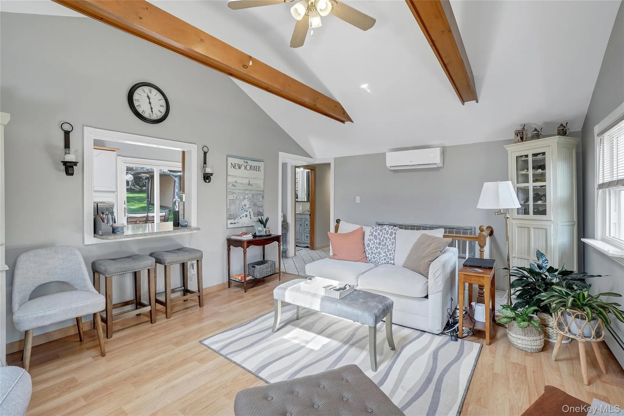 Living area featuring light wood-style flooring, a ceiling fan, and an AC wall unit Living area featuring light wood-style flooring, a ceiling fan, and an AC wall unit