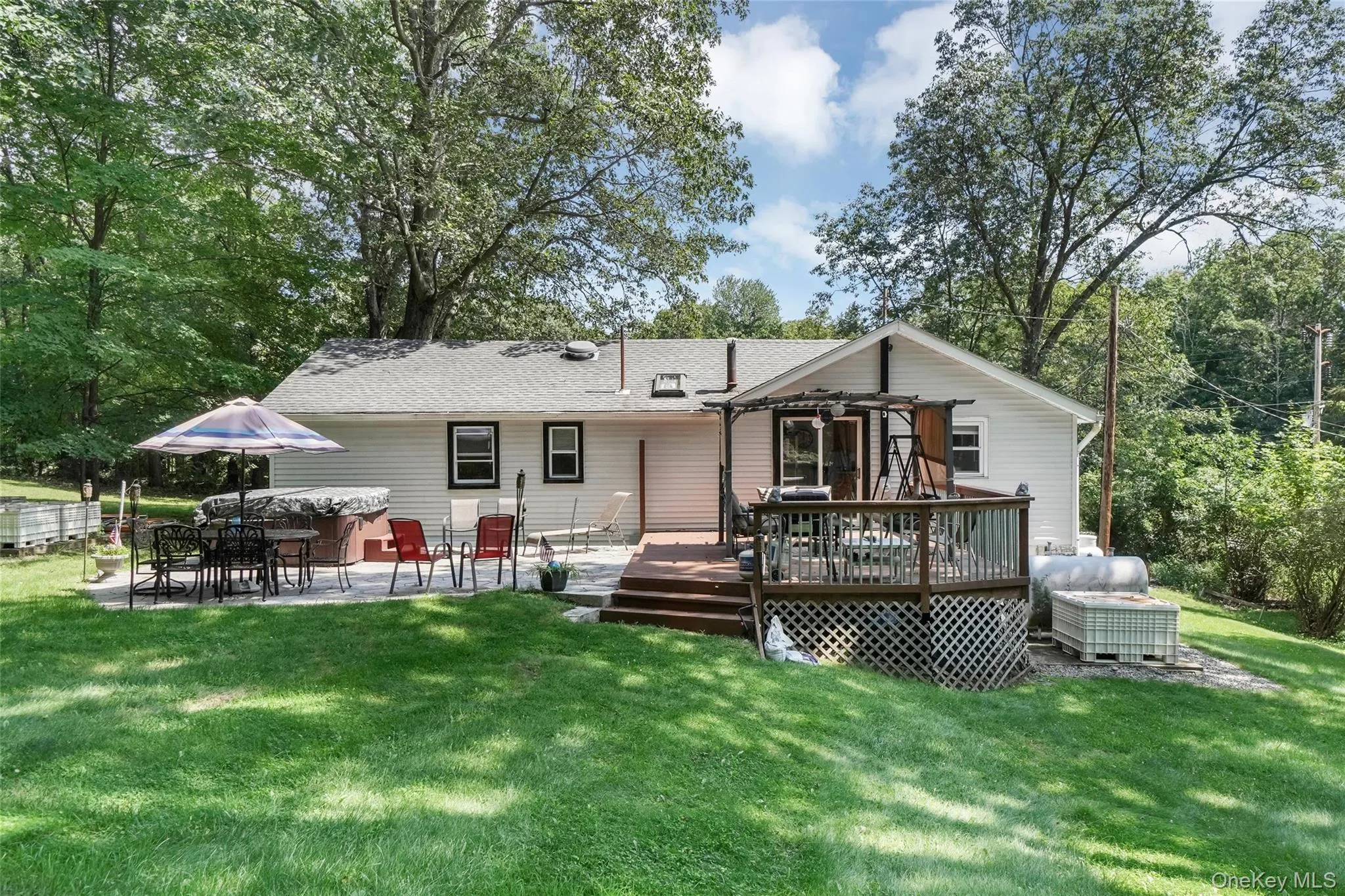 Rear view of property featuring a yard, a jacuzzi, a patio, and a deck Rear view of property featuring a yard, a jacuzzi, a patio, and a deck