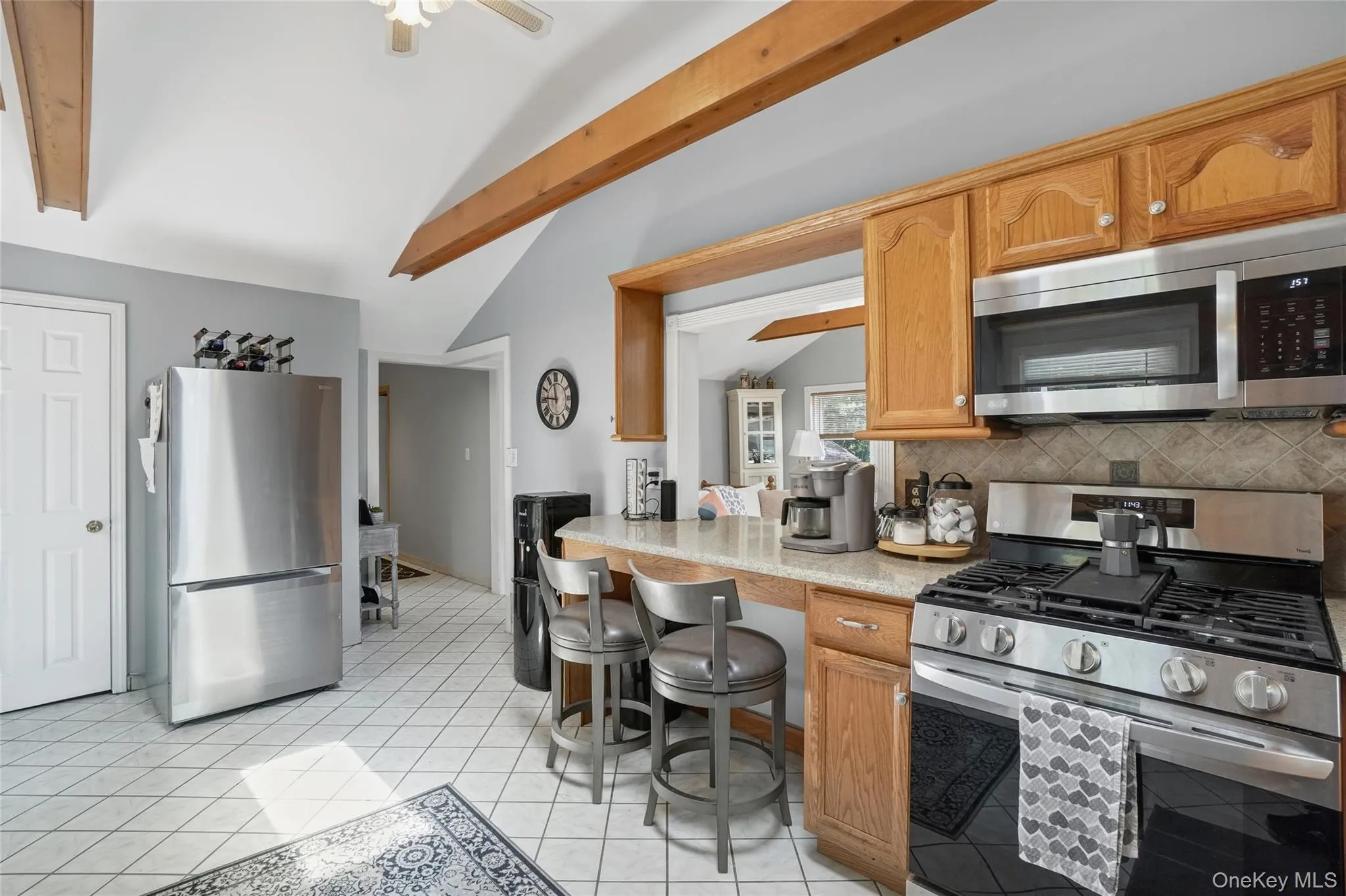 Kitchen with stainless steel appliances, light countertops, tasteful backsplash, light tile patterned floors, and ceiling fan Kitchen with stainless steel appliances, light countertops, tasteful backsplash, light tile patterned floors, and ceiling fan