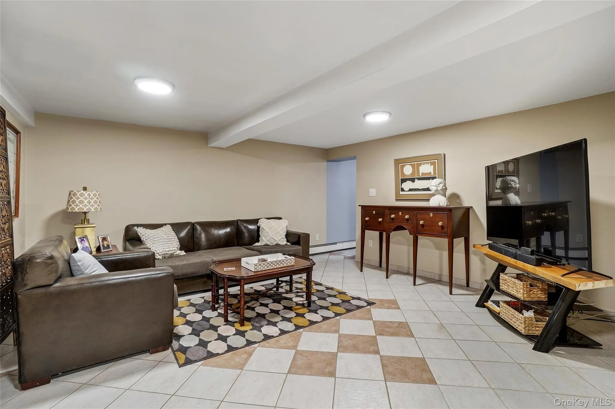 Living room with light tile patterned flooring and a baseboard radiator Living room with light tile patterned flooring and a baseboard radiator