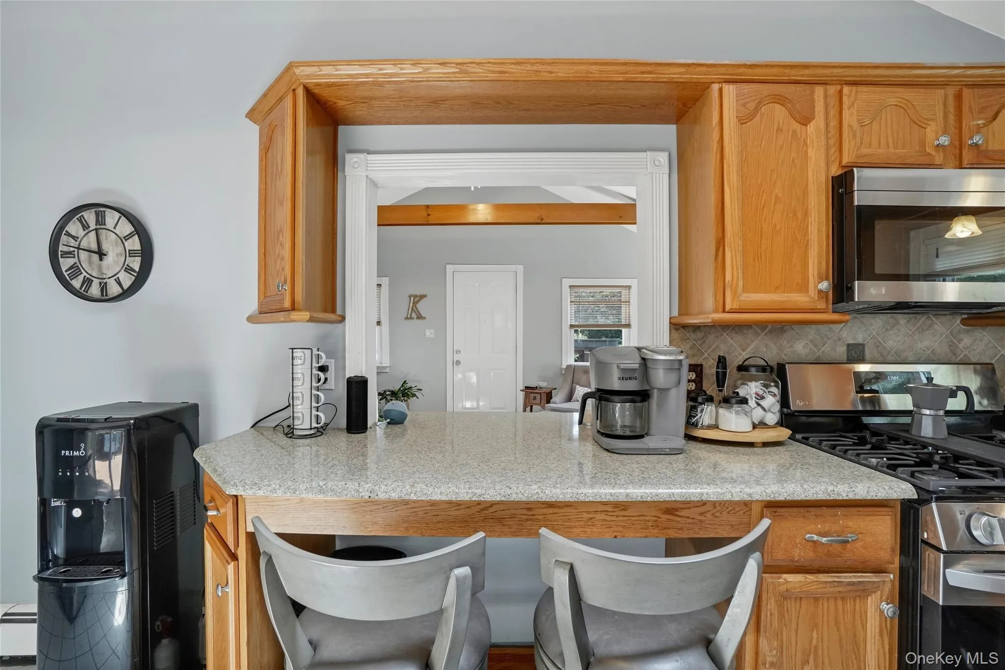 Kitchen with stainless steel appliances, a kitchen breakfast bar, brown cabinets, and backsplash Kitchen with stainless steel appliances, a kitchen breakfast bar, brown cabinets, and backsplash
