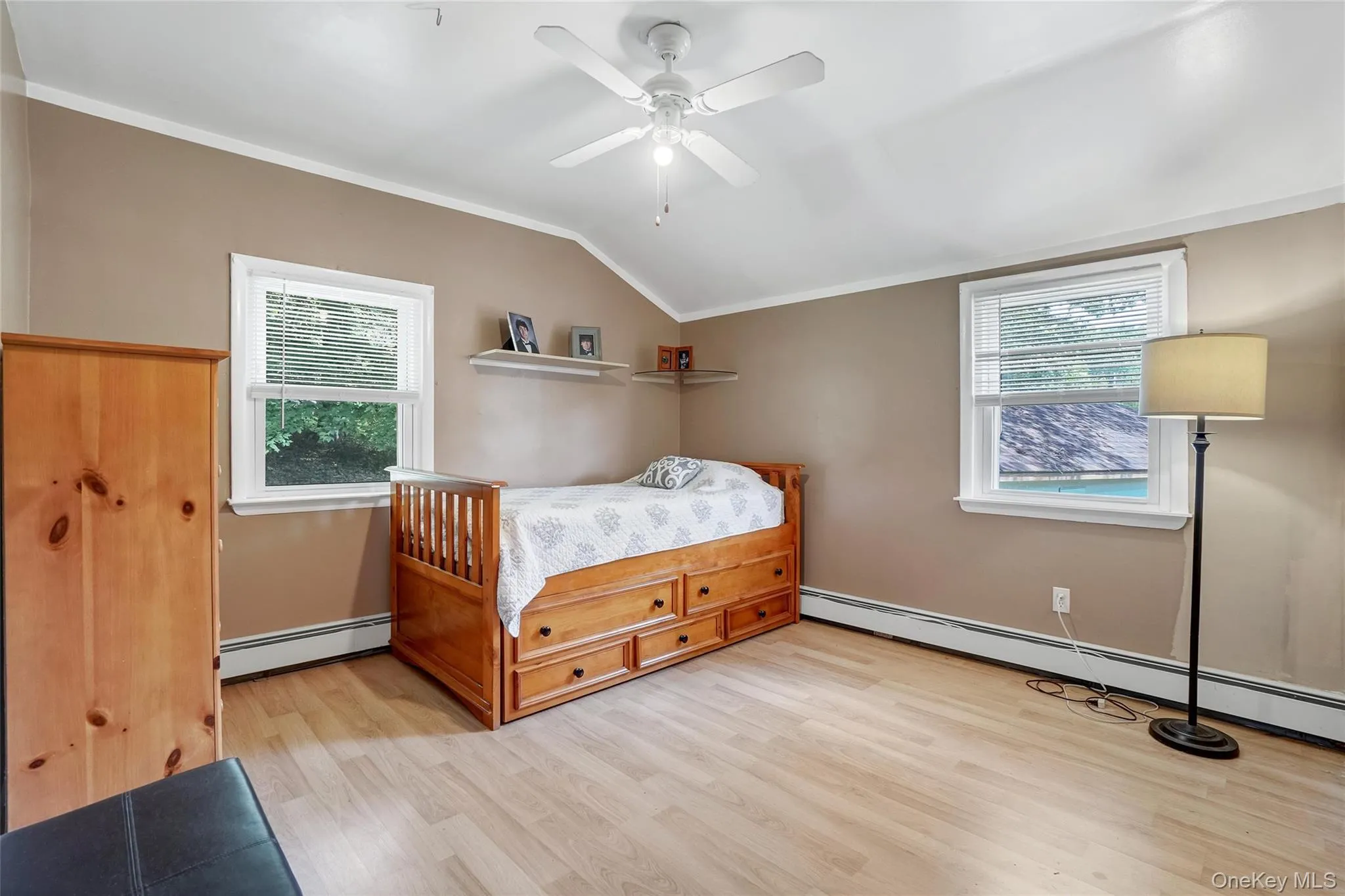 Bedroom with vaulted ceiling, light wood-type flooring, a ceiling fan, and a baseboard heating unit Bedroom with vaulted ceiling, light wood-type flooring, a ceiling fan, and a baseboard heating unit