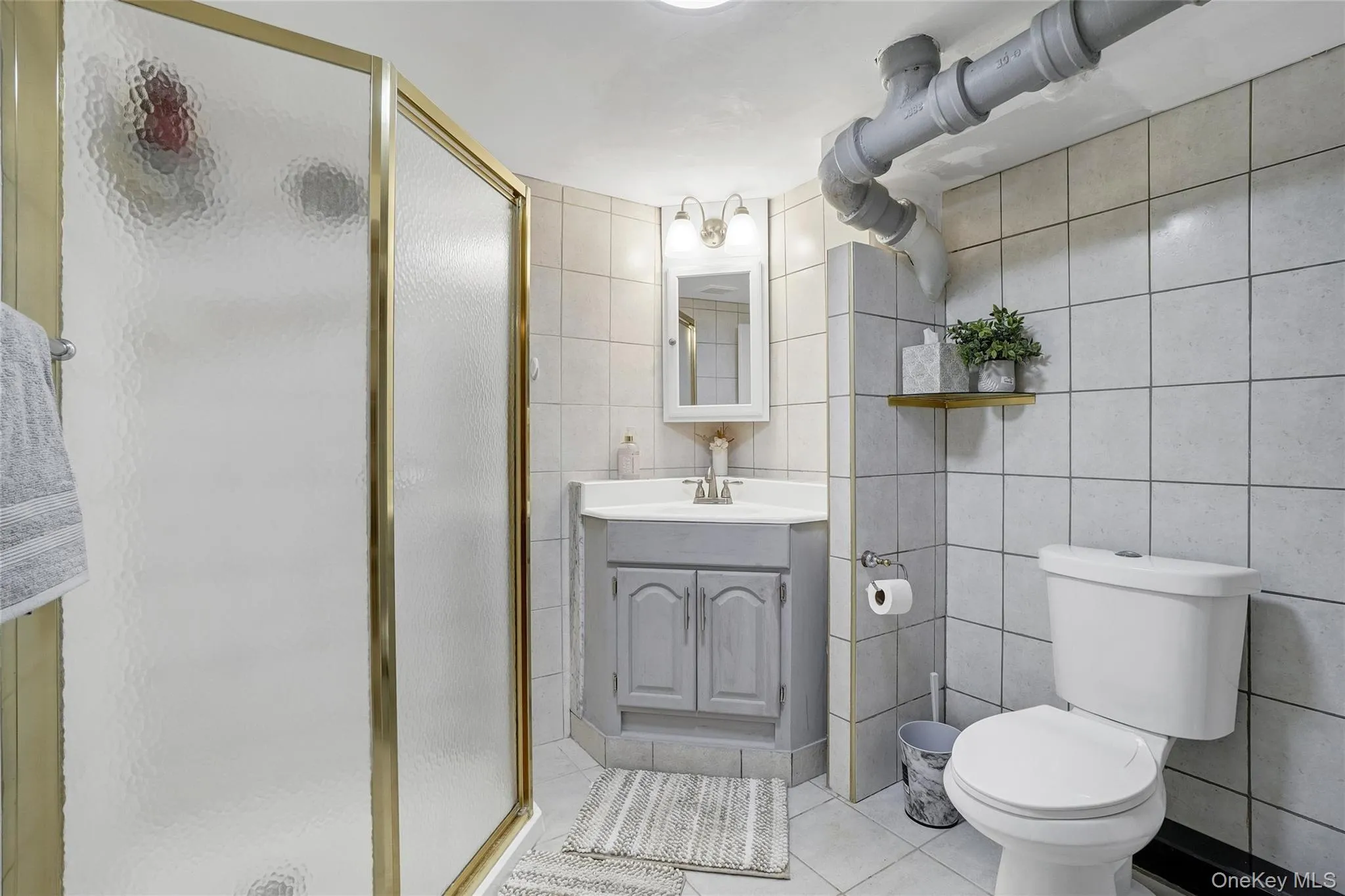 Full bathroom featuring vanity, light tile patterned floors, a stall shower, and tile walls Full bathroom featuring vanity, light tile patterned floors, a stall shower, and tile walls