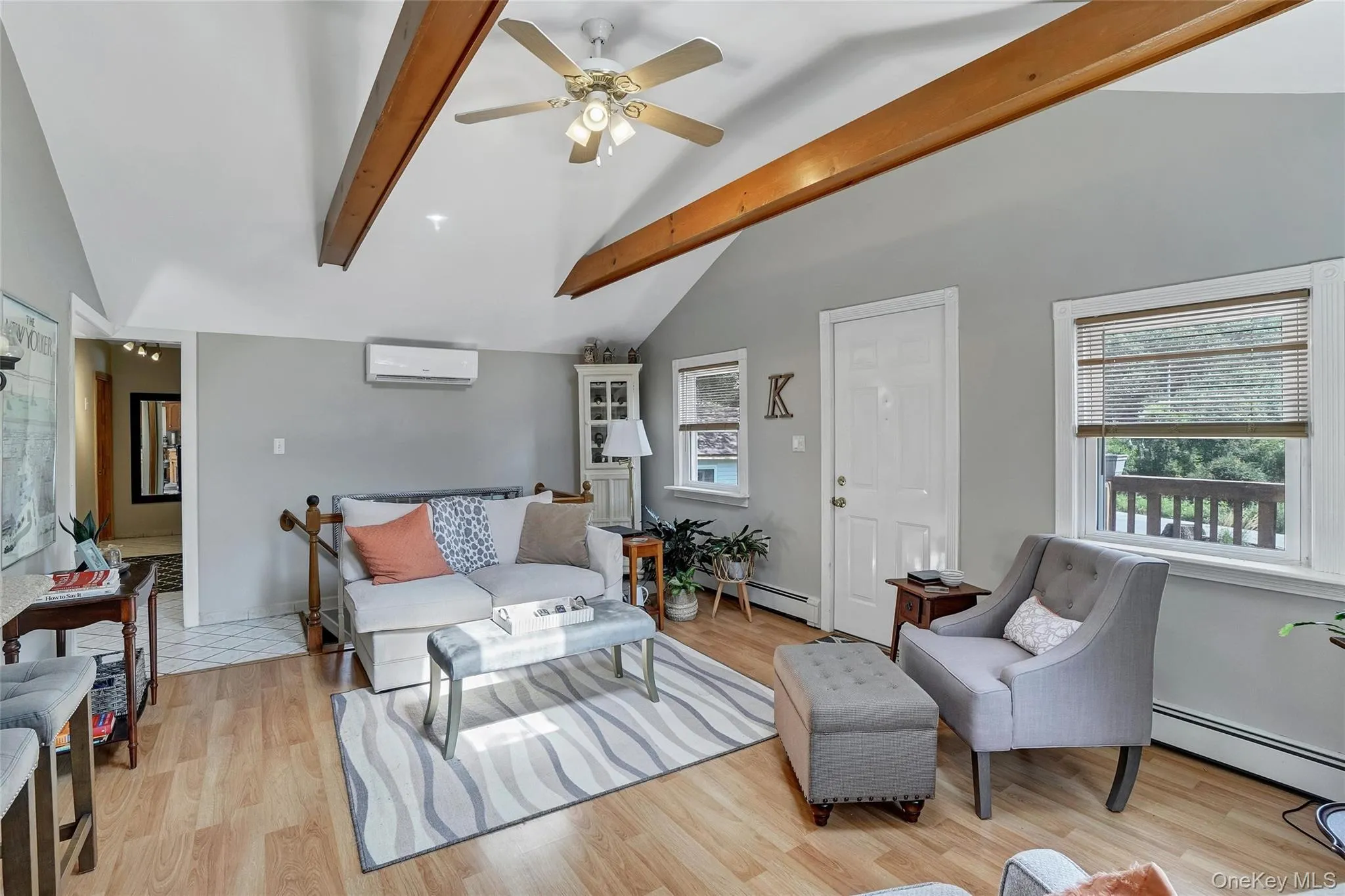 Living area with a ceiling fan, a baseboard heating unit, light wood-style floors, and a wall mounted air conditioner Living area with a ceiling fan, a baseboard heating unit, light wood-style floors, and a wall mounted air conditioner