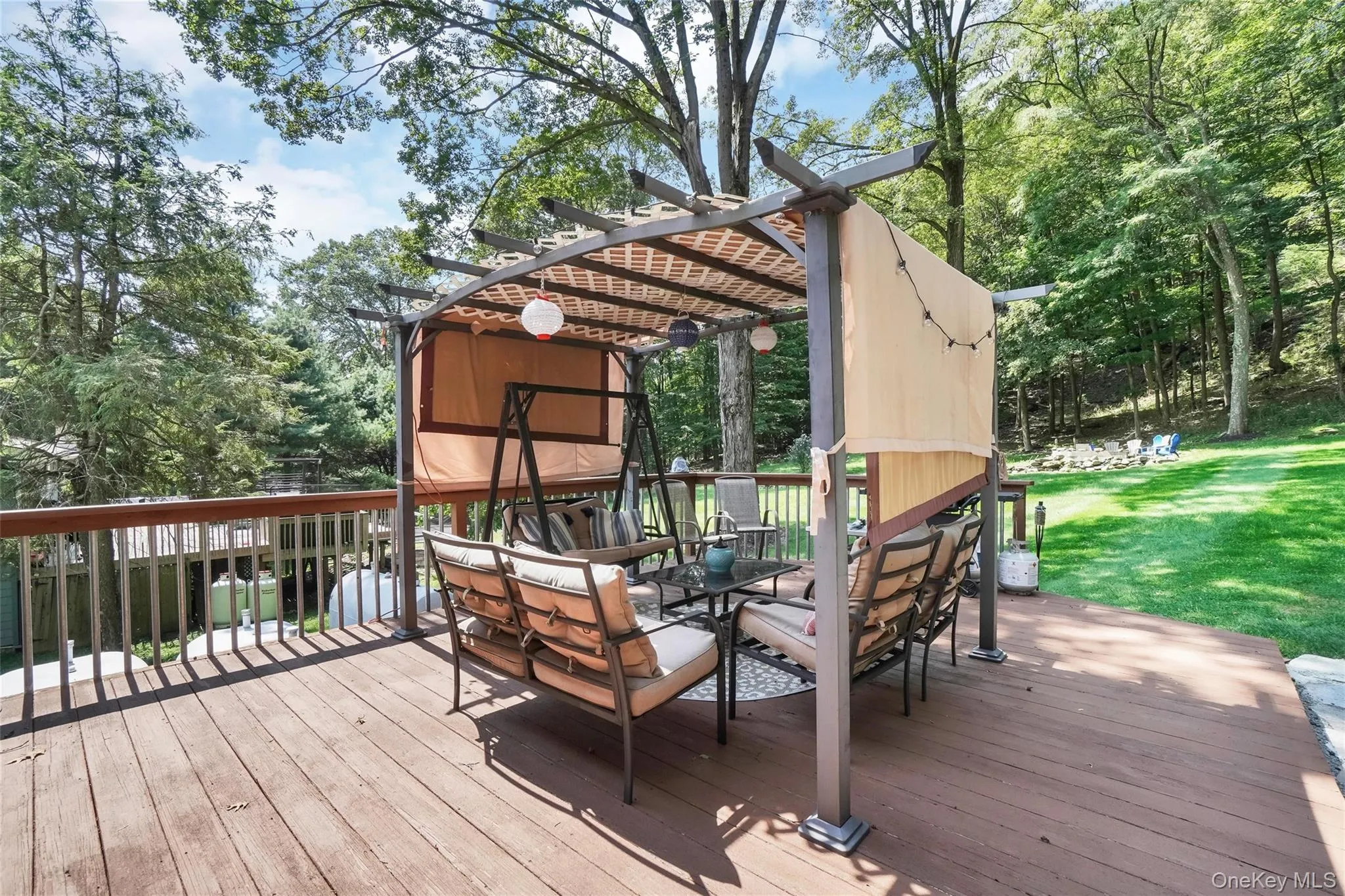 Wooden deck with outdoor dining space, view of scattered trees, and a lawn Wooden deck with outdoor dining space, view of scattered trees, and a lawn