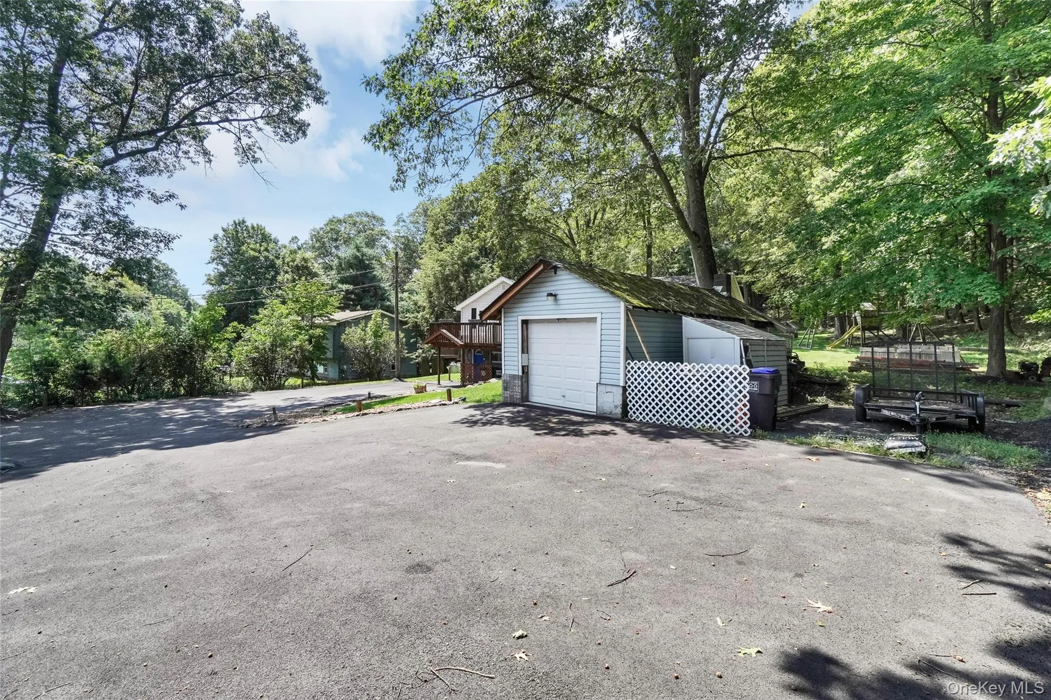 Detached garage featuring view of wooded area and driveway Detached garage featuring view of wooded area and driveway