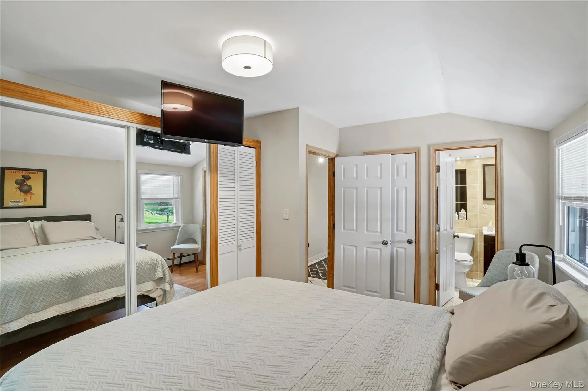 Bedroom with multiple closets, multiple windows, lofted ceiling, connected bathroom, and a baseboard radiator Bedroom with multiple closets, multiple windows, lofted ceiling, connected bathroom, and a baseboard radiator
