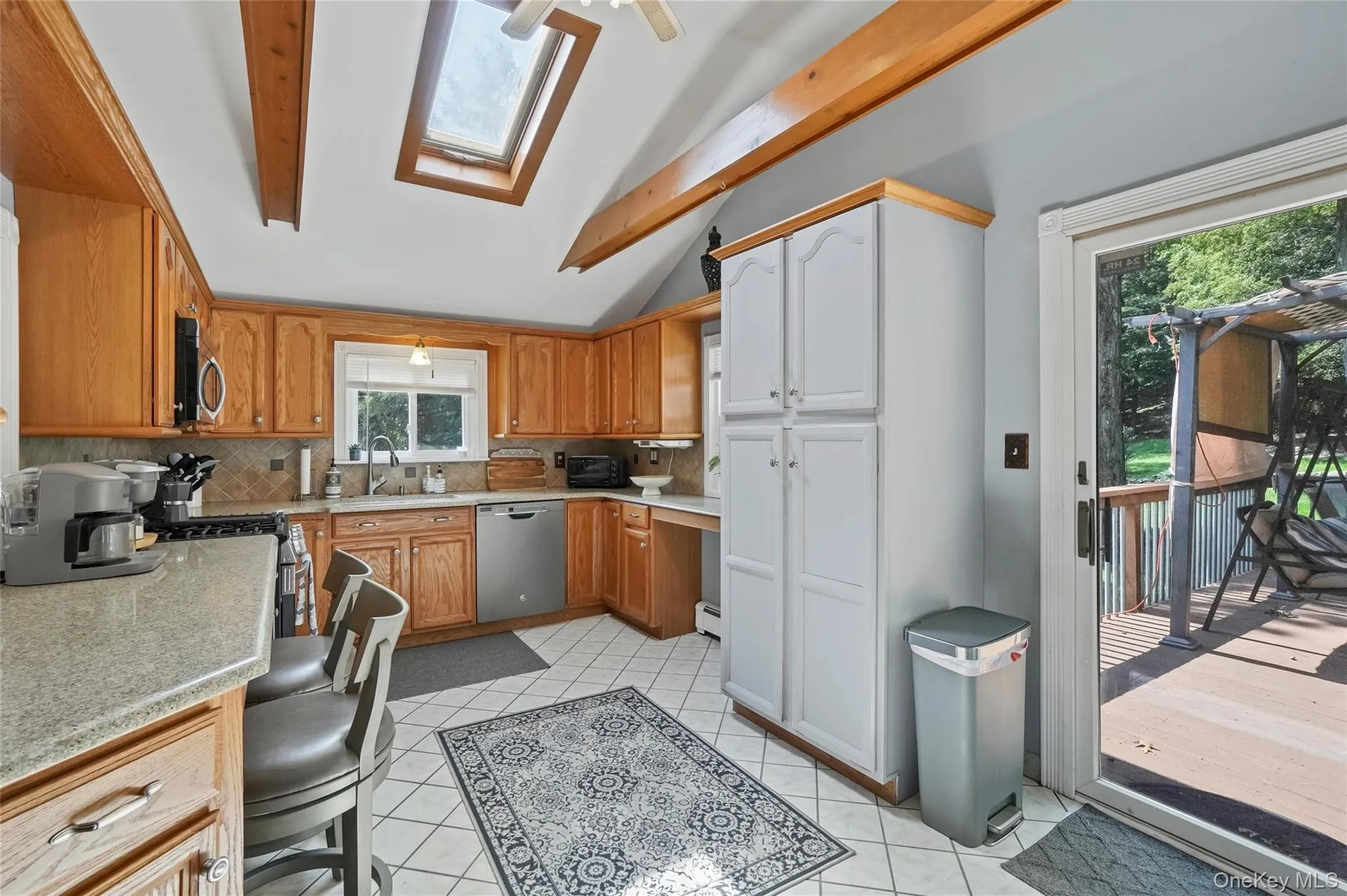 Kitchen with a skylight, tasteful backsplash, stainless steel appliances, and light tile patterned floors Kitchen with a skylight, tasteful backsplash, stainless steel appliances, and light tile patterned floors