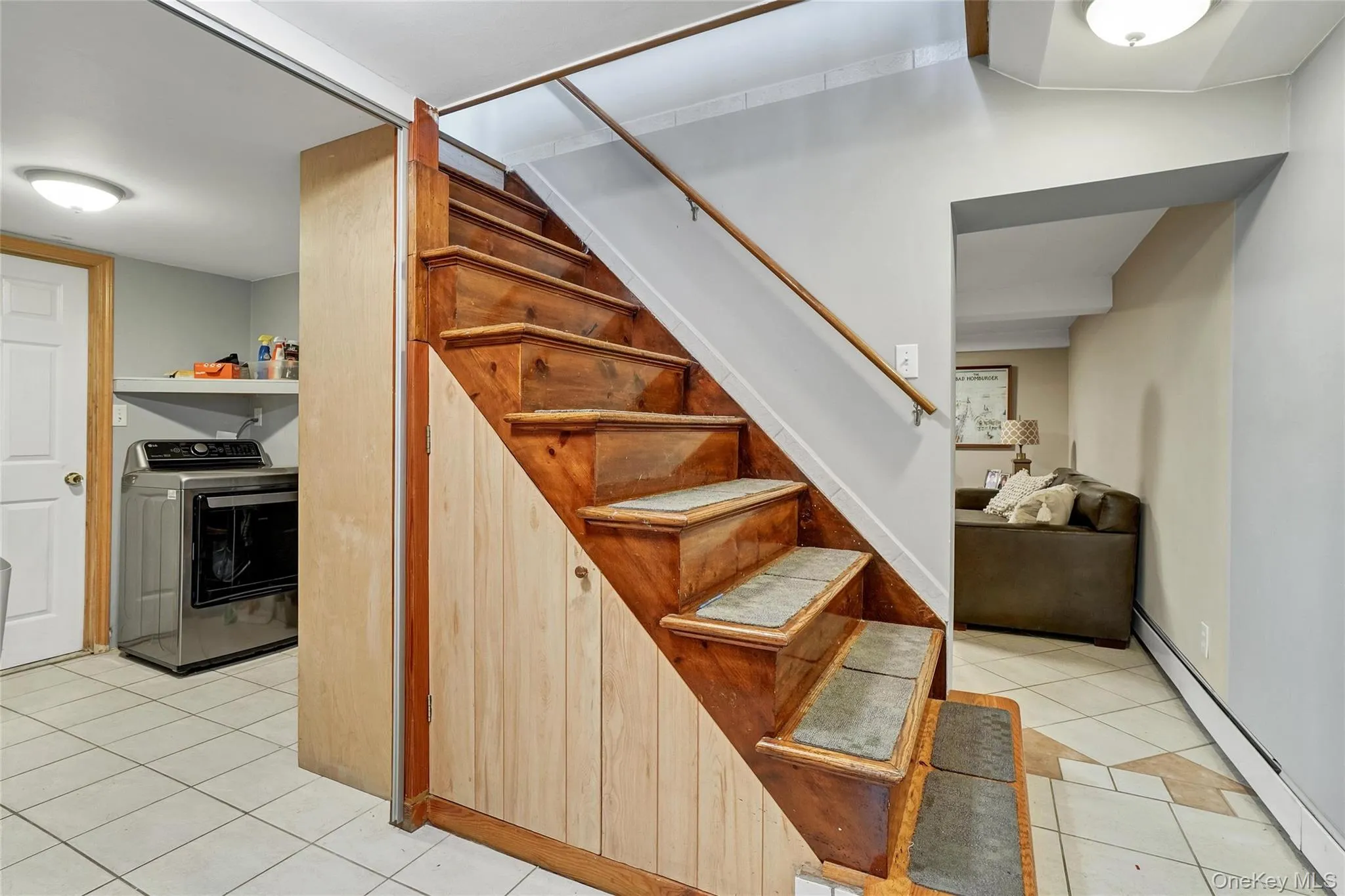 Stairway featuring baseboard heating, washer / clothes dryer, and tile patterned flooring Stairway featuring baseboard heating, washer / clothes dryer, and tile patterned flooring