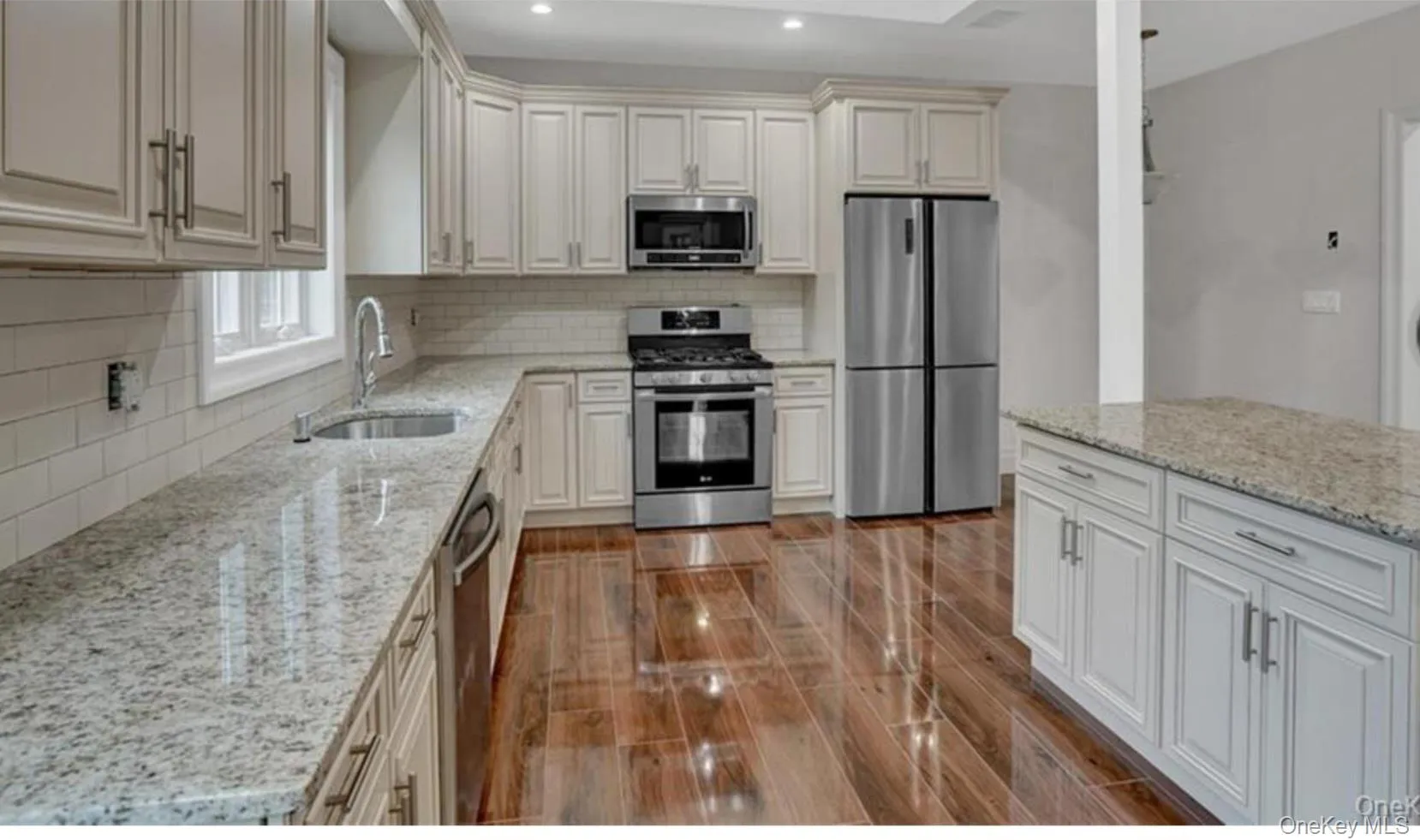 Kitchen with stainless steel appliances, light stone countertops, recessed lighting, decorative backsplash, and wood finish floors Kitchen with stainless steel appliances, light stone countertops, recessed lighting, decorative backsplash, and wood finish floors