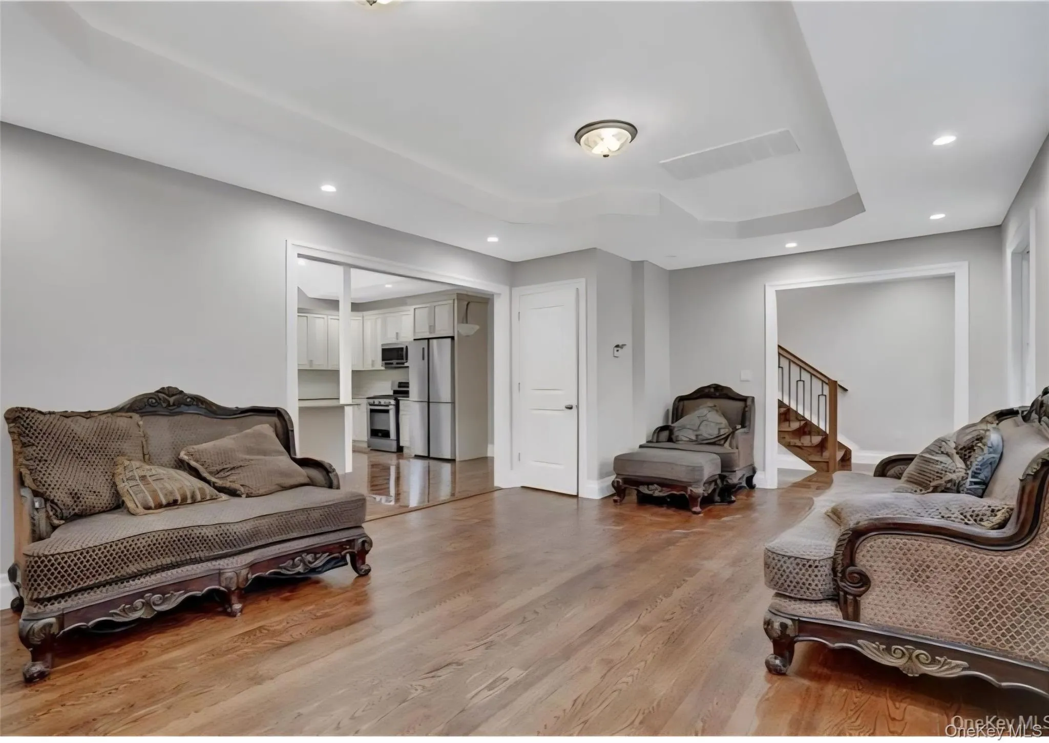 Sitting room featuring light wood-style flooring, recessed lighting, a raised ceiling, and stairway Sitting room featuring light wood-style flooring, recessed lighting, a raised ceiling, and stairway