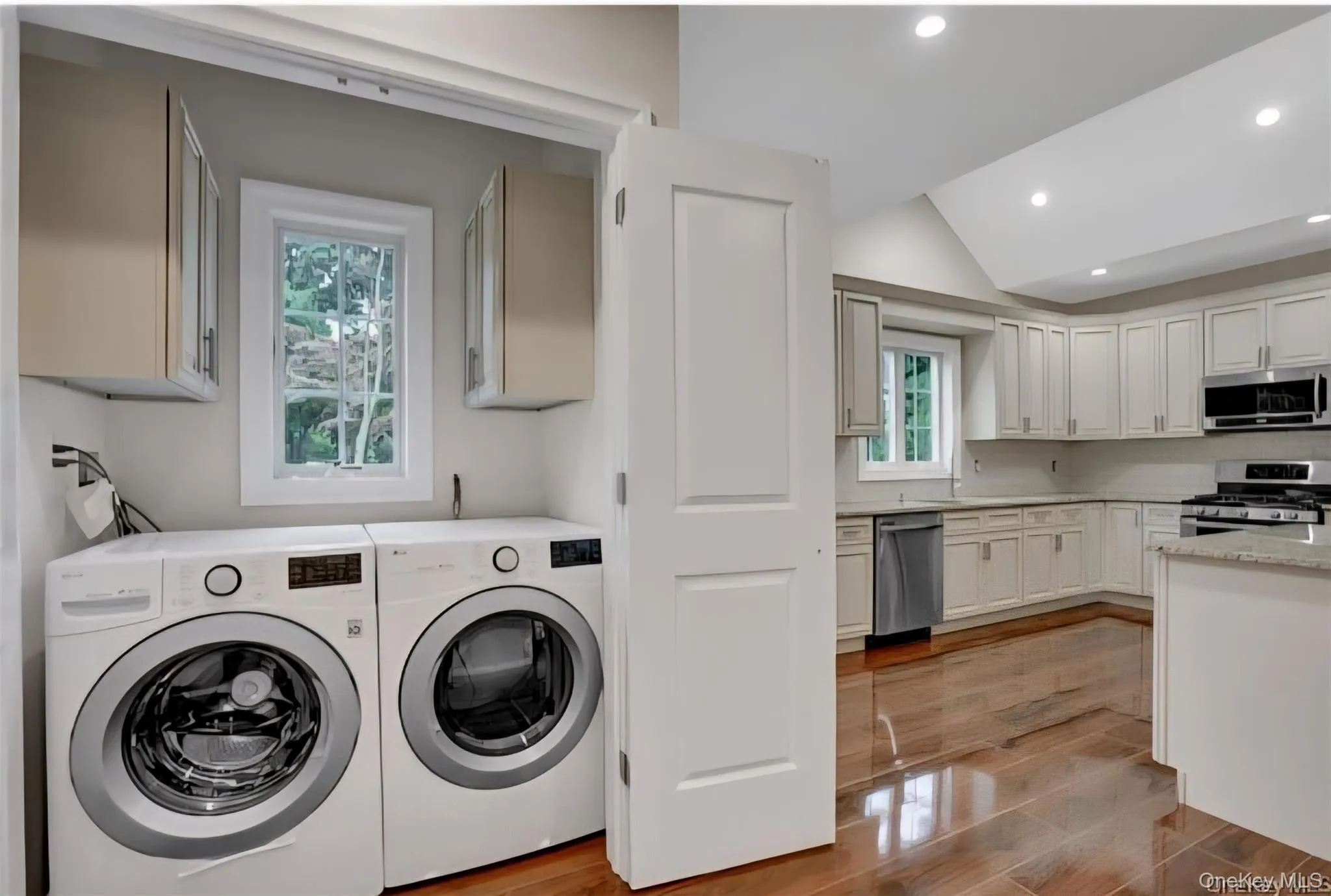 Laundry room featuring washing machine and dryer, lofted ceiling, recessed lighting, cabinet space, and light wood-style floors Laundry room featuring washing machine and dryer, lofted ceiling, recessed lighting, cabinet space, and light wood-style floors