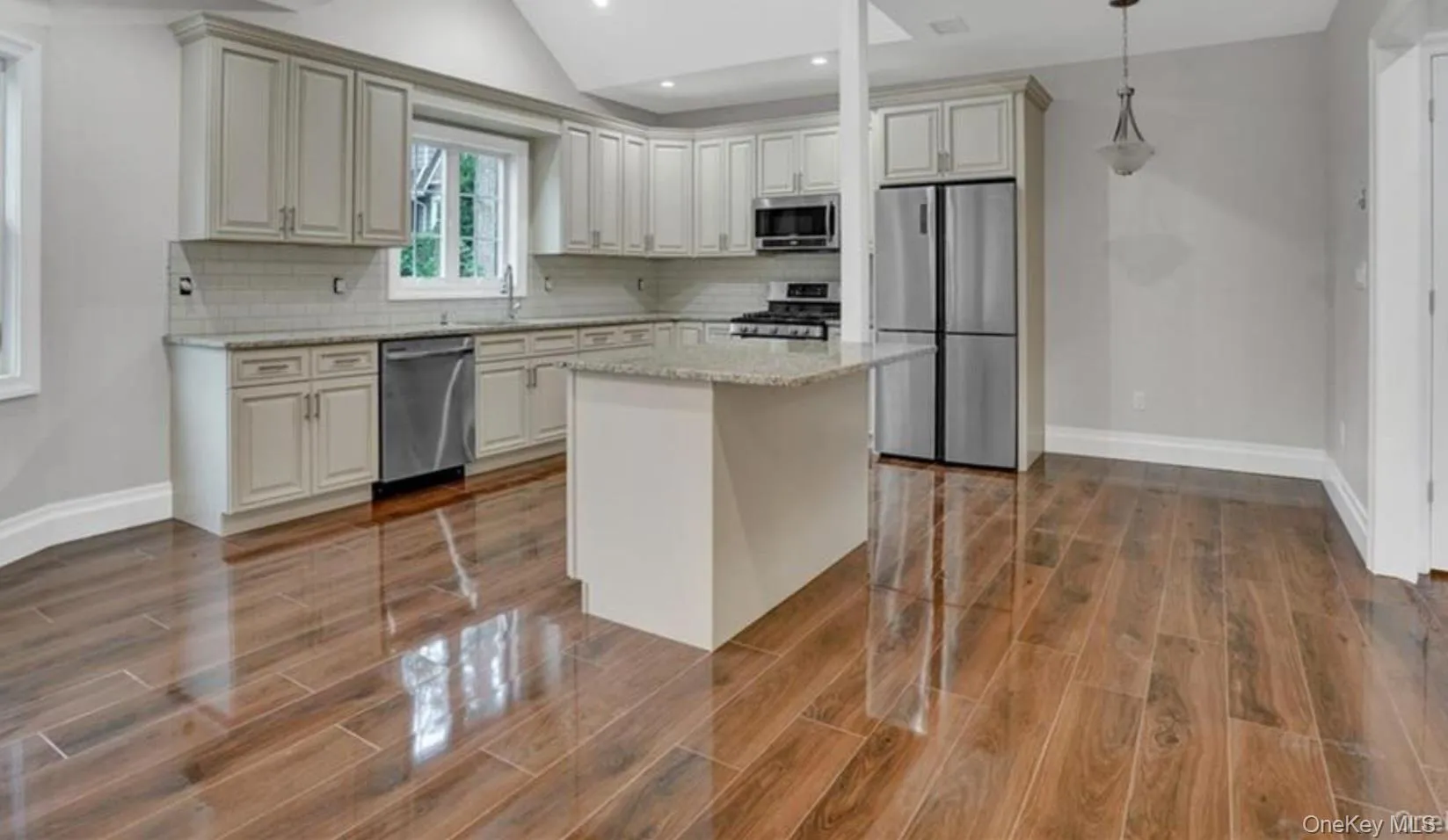 Kitchen featuring appliances with stainless steel finishes, light stone counters, decorative light fixtures, decorative backsplash, and a center island Kitchen featuring appliances with stainless steel finishes, light stone counters, decorative light fixtures, decorative backsplash, and a center island