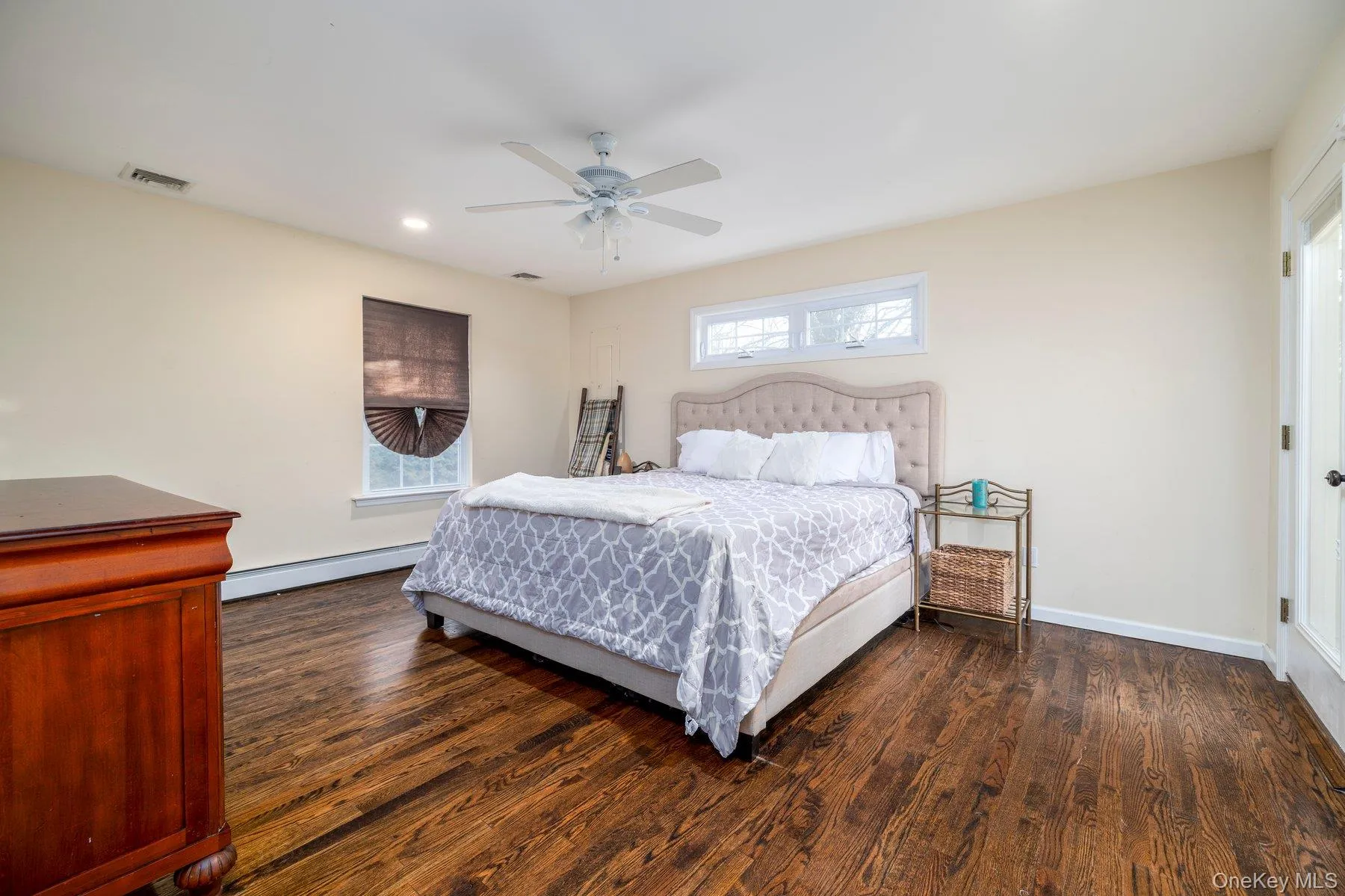 Bedroom featuring dark wood-style flooring, a baseboard heating unit, a ceiling fan, and recessed lighting Bedroom featuring dark wood-style flooring, a baseboard heating unit, a ceiling fan, and recessed lighting