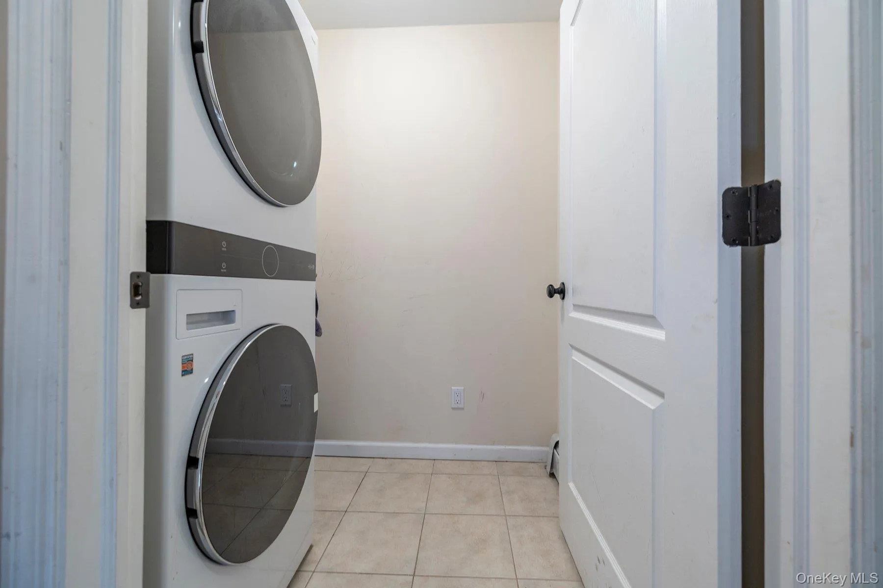 Laundry room featuring light tile patterned floors and estacked washer and dryer Laundry room featuring light tile patterned floors and estacked washer and dryer