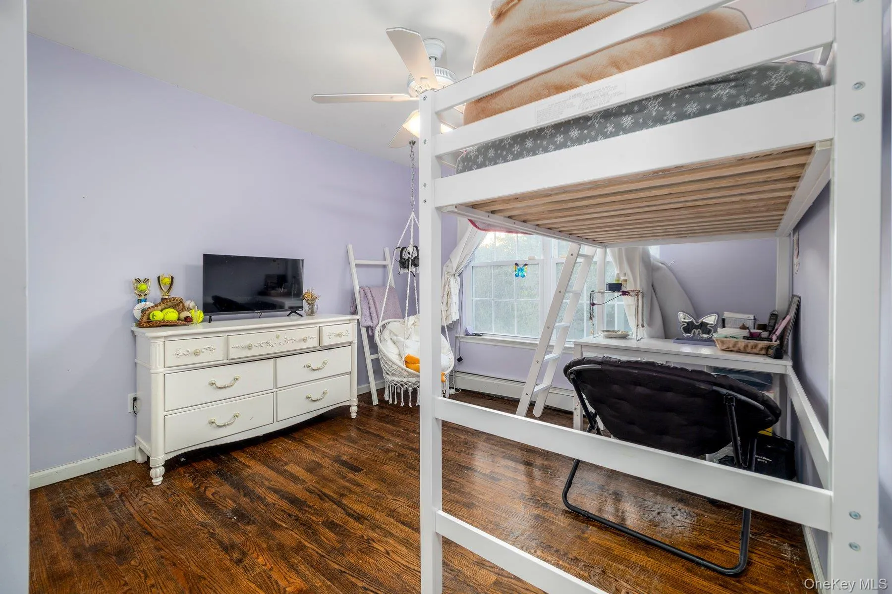 Bedroom with a ceiling fan, dark wood-style floors, and a baseboard heating unit Bedroom with a ceiling fan, dark wood-style floors, and a baseboard heating unit